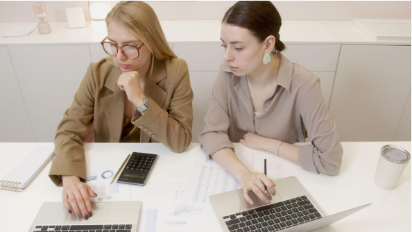Two colleagues reviewing a small business IT budget on laptops