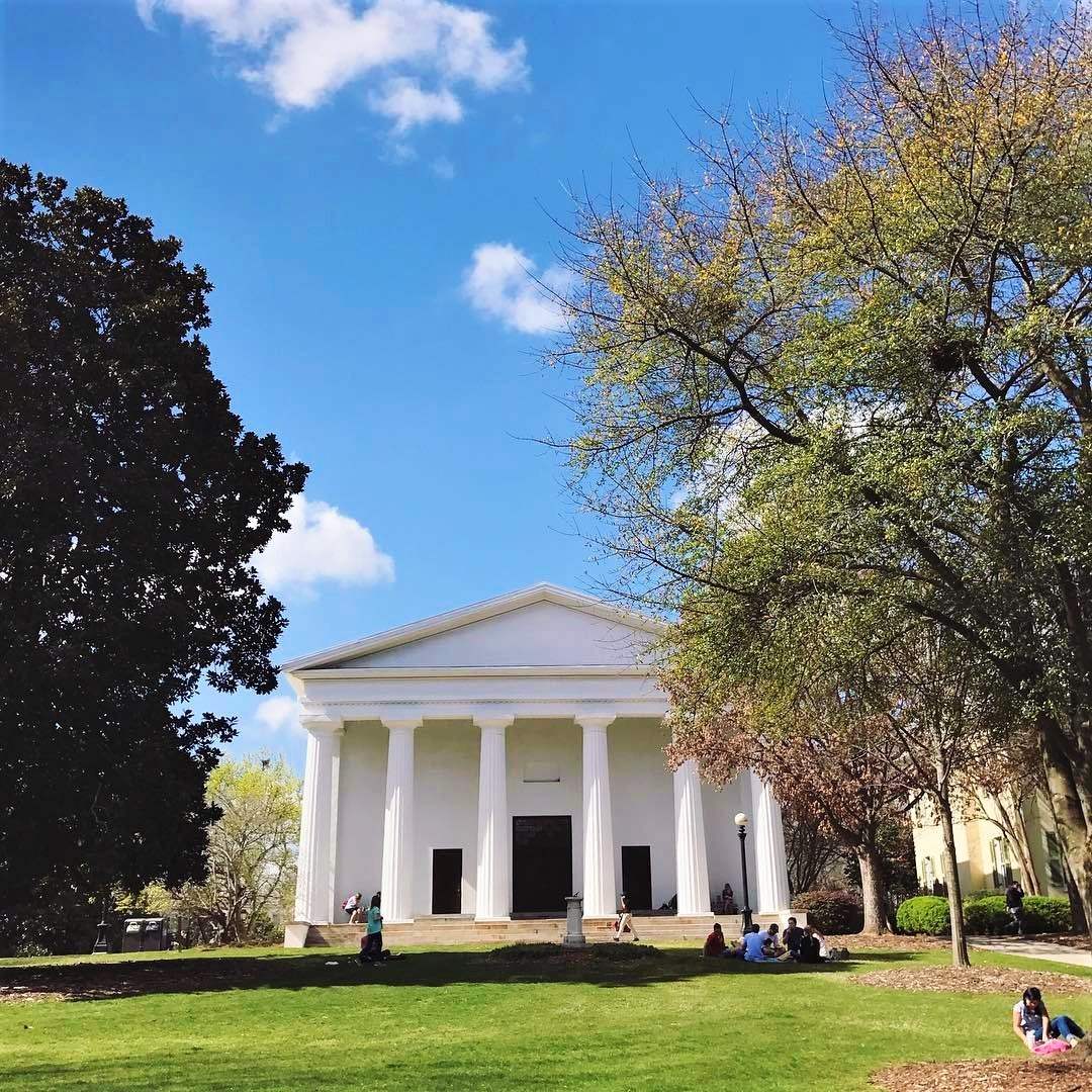 The white-columned UGA Chapel behind a green lawn under a blue sky.