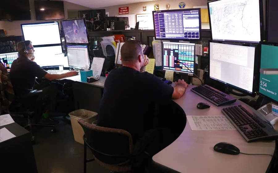 Emergency dispatch center with staff working at multi-monitor consoles