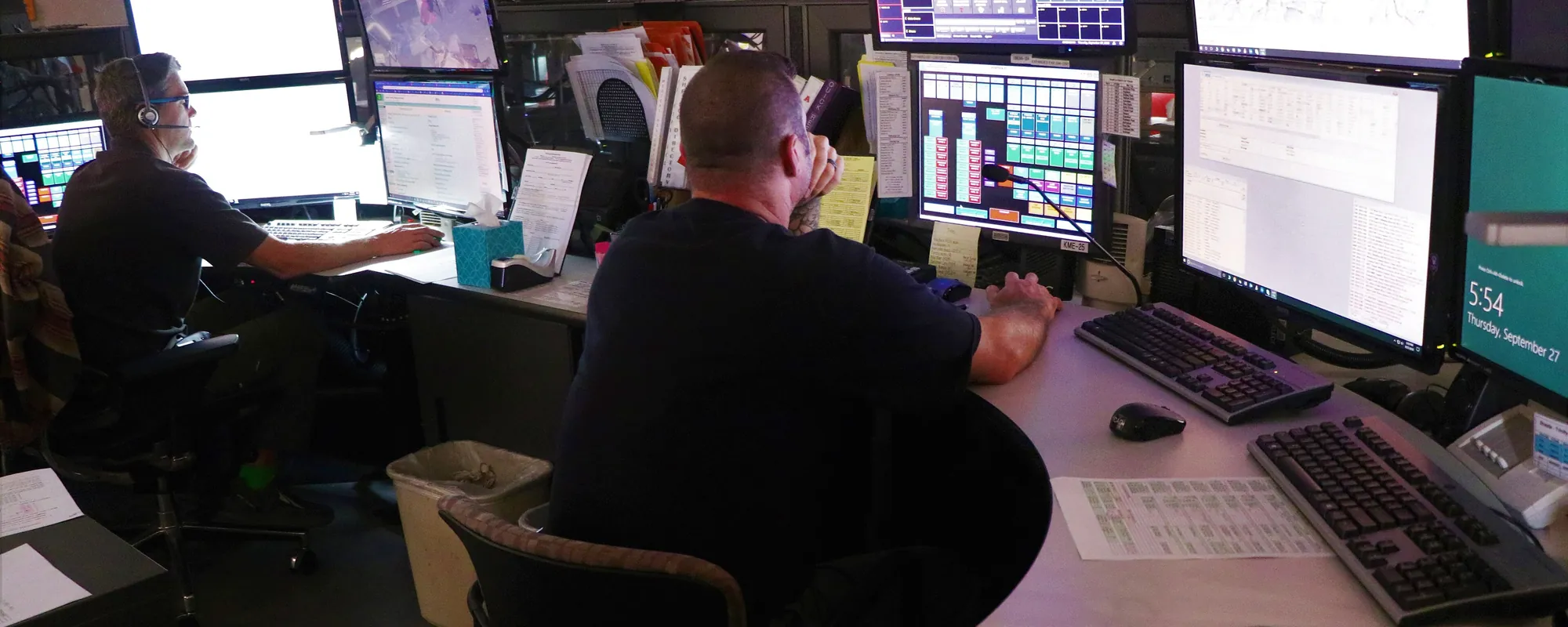 Emergency dispatch center with staff working at multi-monitor consoles