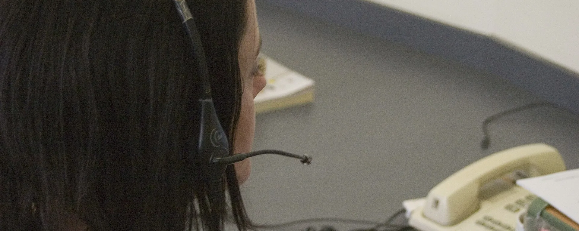 Person wearing a headset at a desk next to a desk phone