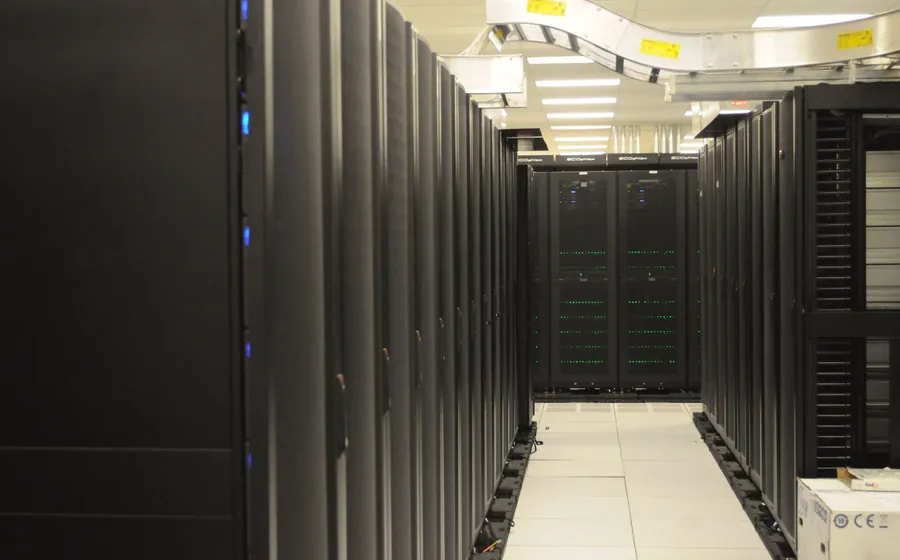 Long aisle of black server racks with status lights in a data center