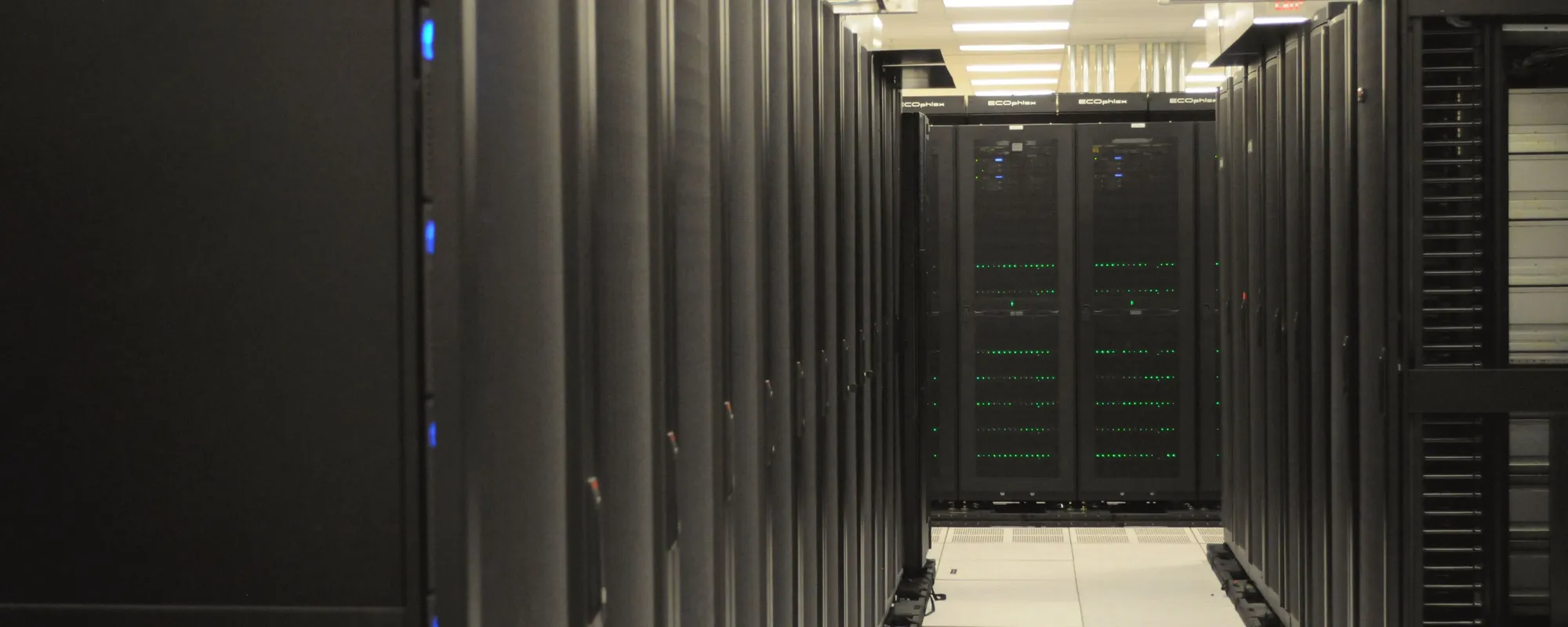 Long aisle of black server racks with status lights in a data center