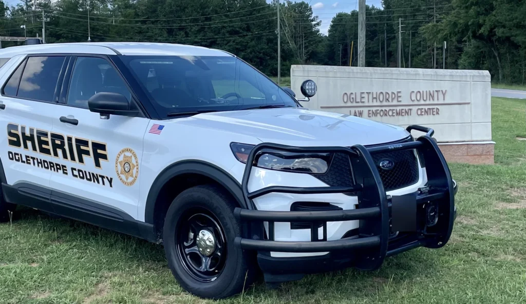 Oglethorpe County Sheriff's Office patrol SUV parked beside the Oglethorpe County Law Enforcement Center sign